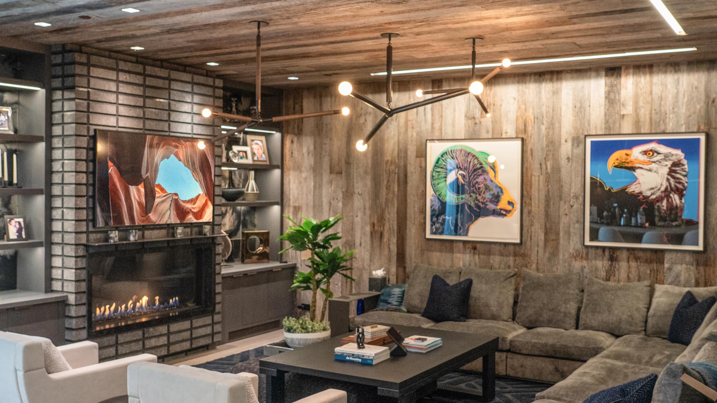 A cozy living room with a large sectional sofa, modern artwork, and a fireplace, designed for a stylish and comfortable entertainment experience.