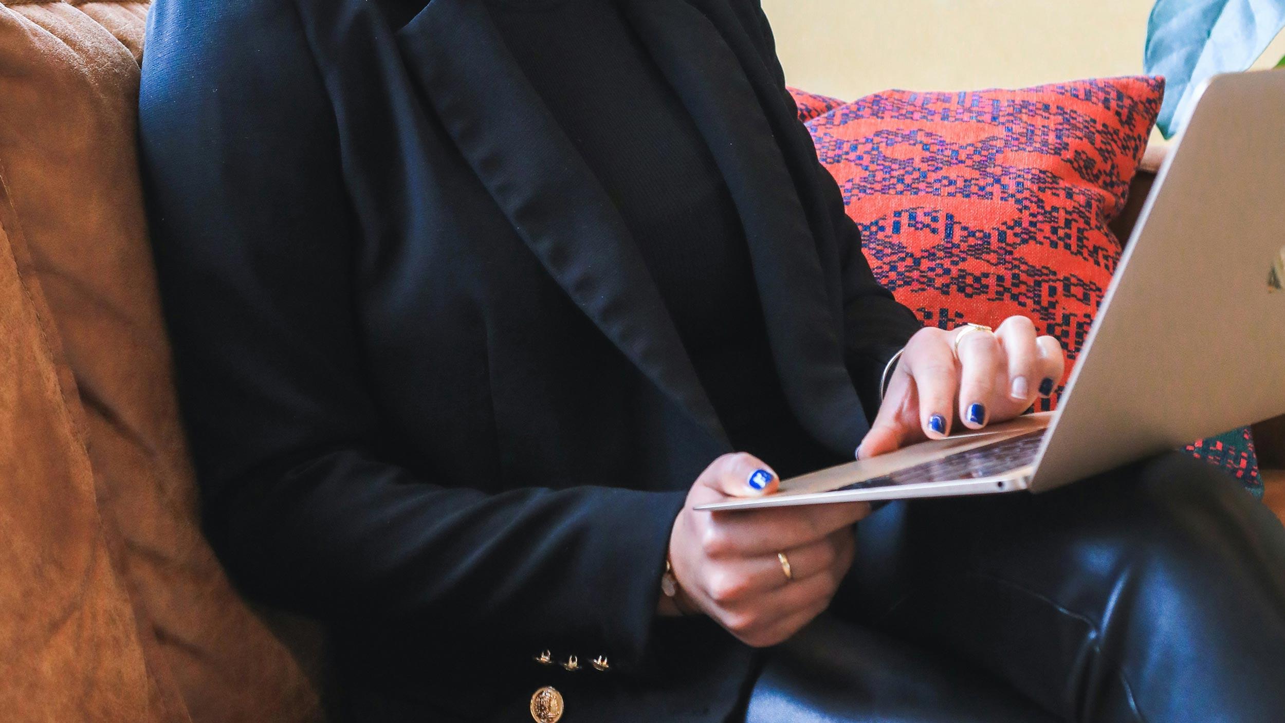 A person using a laptop on a couch, illustrating a comfortable environment for working or browsing online.